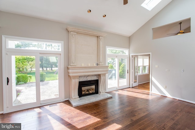unfurnished living room with ceiling fan, wood finished floors, and high vaulted ceiling