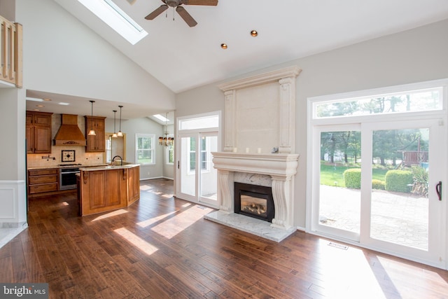 unfurnished living room with dark wood-style flooring, ceiling fan, a premium fireplace, high vaulted ceiling, and visible vents