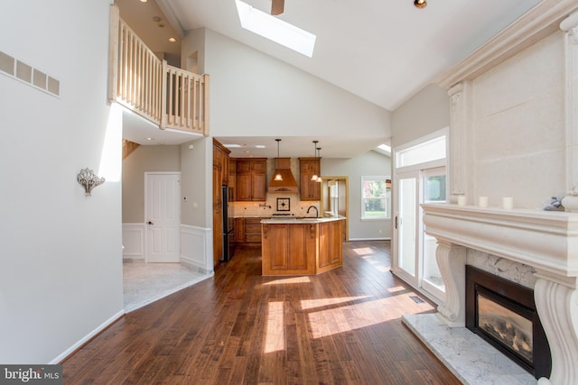living room featuring high vaulted ceiling, a high end fireplace, a skylight, visible vents, and dark wood-style floors