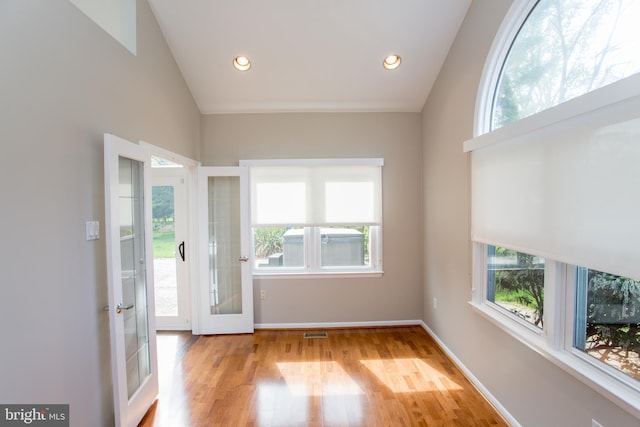 doorway featuring baseboards, visible vents, vaulted ceiling, and light wood-style floors