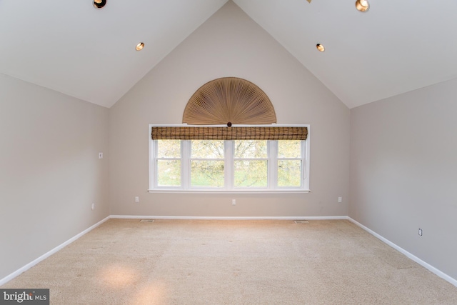 spare room with baseboards, light carpet, and lofted ceiling