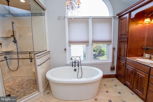 full bath with tile patterned flooring, vanity, baseboards, a soaking tub, and a stall shower