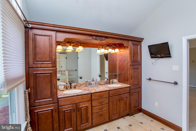 full bathroom featuring double vanity, a sink, baseboards, and lofted ceiling