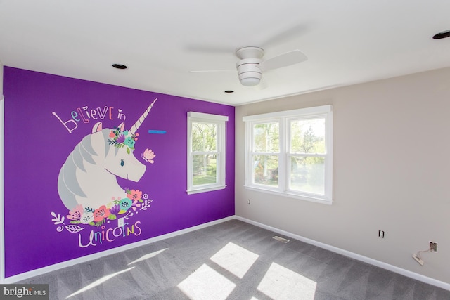 empty room featuring carpet flooring, a ceiling fan, baseboards, and visible vents