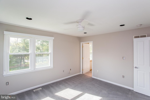 carpeted spare room featuring baseboards, ceiling fan, and visible vents