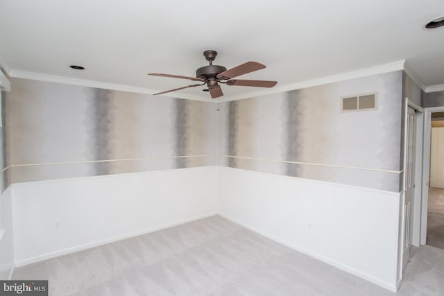 empty room with crown molding, carpet, a ceiling fan, baseboards, and visible vents