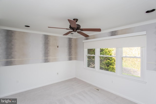 empty room with visible vents, a ceiling fan, light colored carpet, and ornamental molding