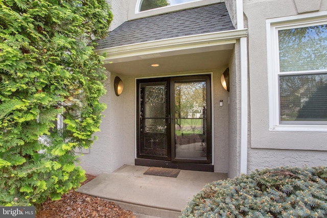 doorway to property with a shingled roof and stucco siding
