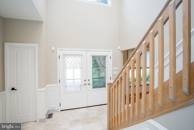 foyer with visible vents, marble finish floor, stairs, a towering ceiling, and french doors