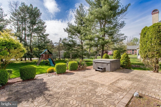 view of patio / terrace featuring a playground and a hot tub
