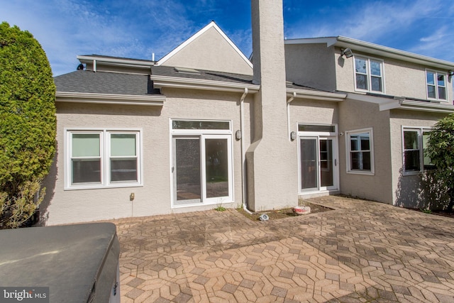 back of house with a patio, a chimney, and stucco siding