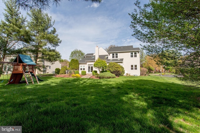 back of property with a lawn, a playground, a patio area, and stucco siding