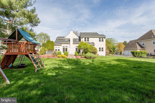 back of house featuring a playground, a chimney, and a yard