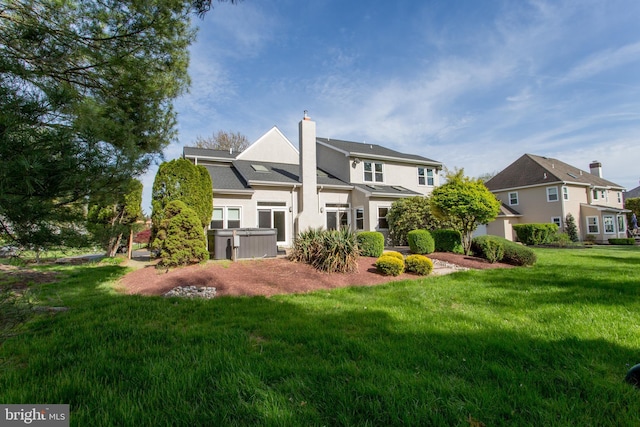 back of house with a lawn, stucco siding, and a chimney