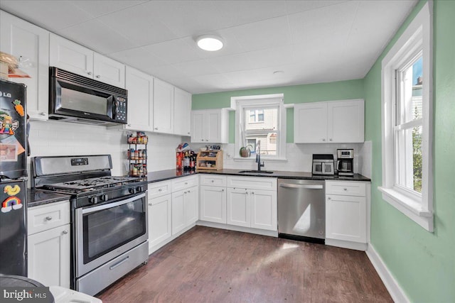 kitchen featuring dark countertops, dark wood-style floors, a sink, and black appliances