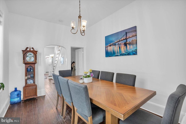 dining area featuring dark wood finished floors, stairway, arched walkways, baseboards, and a notable chandelier
