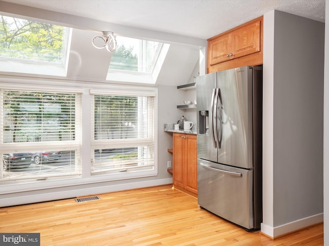 504 Moorings Cir, Arnold, MD 21012 - kitchen featuring vaulted ceiling with skylight, visible vents, light wood-style flooring, baseboards, and stainless steel fridge with ice dispenser