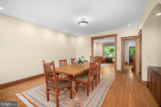 dining room with arched walkways, baseboards, light wood finished floors, radiator heating unit, and recessed lighting