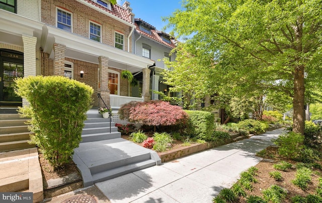 entrance to property with covered porch and brick siding