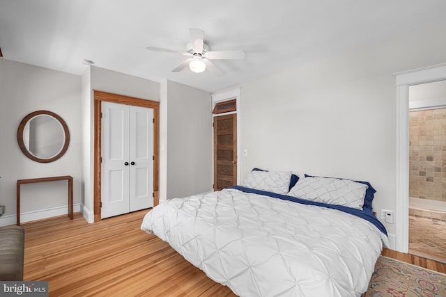 bedroom with ceiling fan, baseboards, a closet, ensuite bathroom, and light wood-style flooring