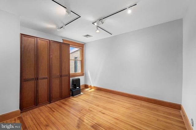 unfurnished bedroom with rail lighting, visible vents, baseboards, and light wood-style floors