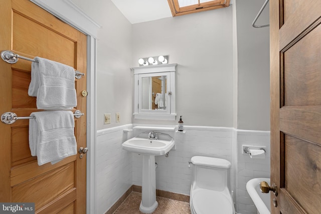 bathroom featuring toilet, tile patterned floors, wainscoting, and a sink