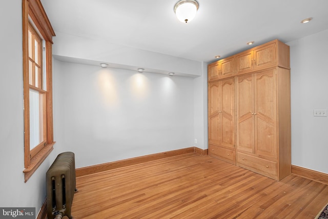 spare room with radiator, baseboards, recessed lighting, and wood finished floors