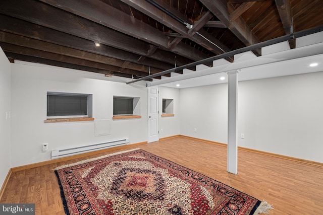 finished below grade area with baseboards, baseboard heating, and wood finished floors