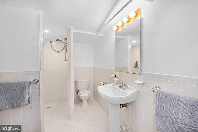 full bath with toilet, a sink, tile walls, and tiled shower
