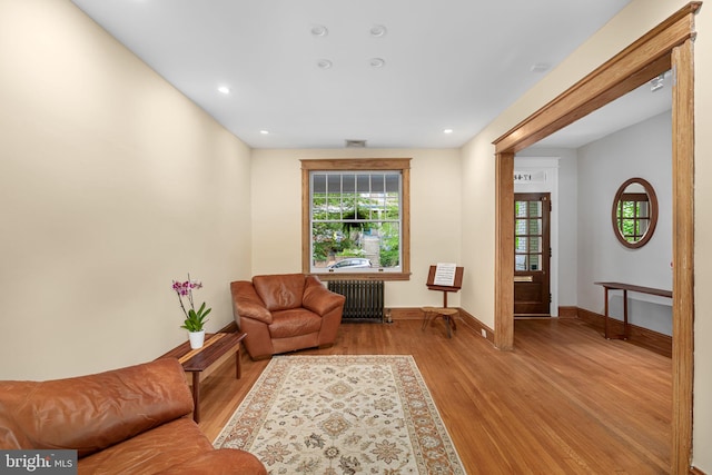 sitting room with baseboards, a wealth of natural light, radiator heating unit, and light wood finished floors