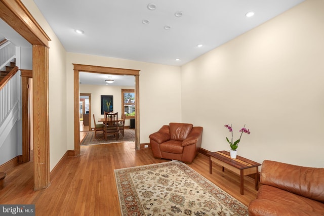 living area with baseboards, recessed lighting, light wood finished floors, and stairs