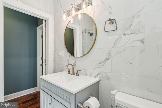 bathroom featuring baseboards, wood finished floors, toilet, and vanity