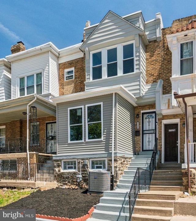 townhome / multi-family property with a chimney, central AC, and covered porch