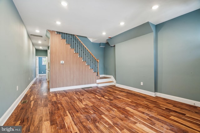 unfurnished living room featuring wood finished floors, baseboards, recessed lighting, and stairs