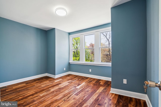 spare room featuring wood finished floors and baseboards