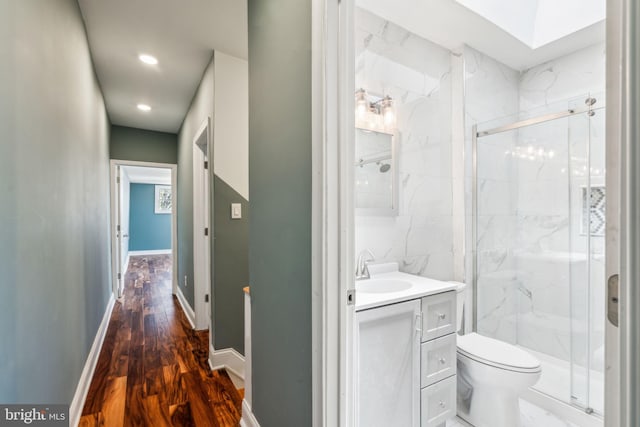 full bathroom with baseboards, a marble finish shower, toilet, wood finished floors, and vanity