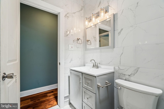 half bath featuring toilet, tile walls, and vanity