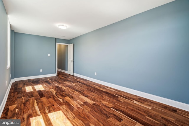 empty room featuring dark wood-style flooring and baseboards