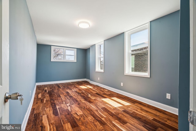 spare room featuring dark wood-style floors and baseboards