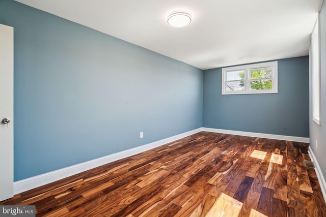 unfurnished room featuring baseboards and dark wood-style flooring