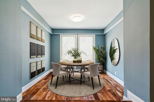 dining space with baseboards and wood finished floors