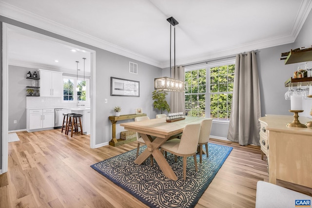 dining room with a healthy amount of sunlight, ornamental molding, light wood-type flooring, and visible vents