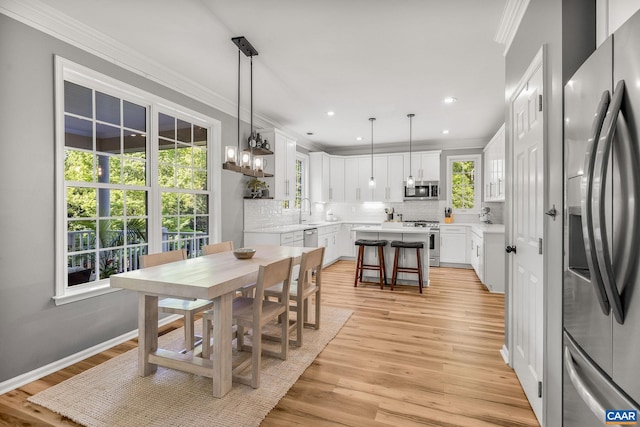 dining room featuring crown molding, recessed lighting, and light wood-style floors