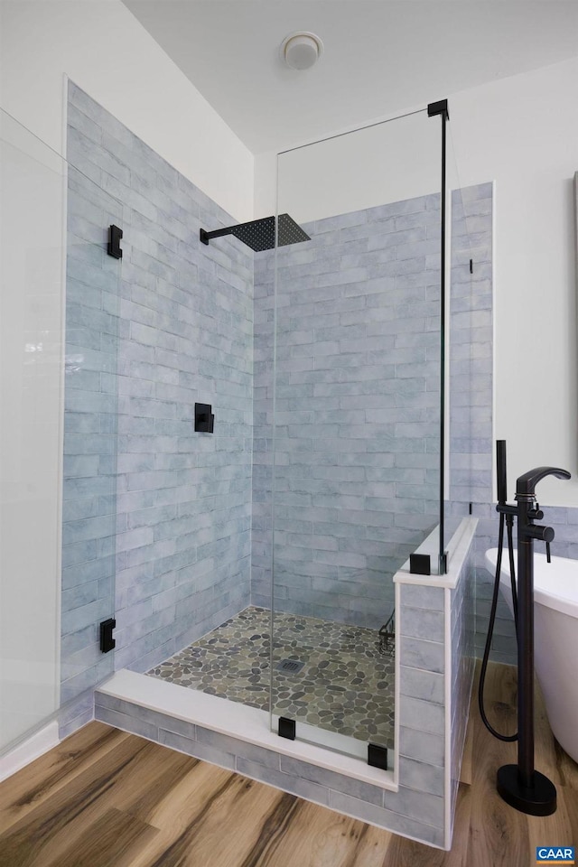 full bathroom with a soaking tub, a shower stall, and wood finished floors
