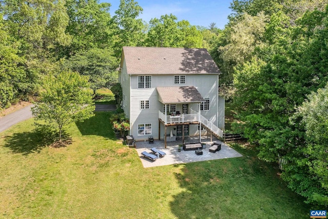 back of house featuring a patio, a shingled roof, a lawn, and a wooden deck