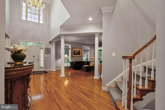 entryway with ornate columns, plenty of natural light, stairs, and ornamental molding