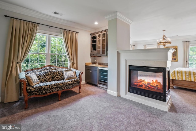 sitting room featuring carpet floors, bar with sink, crown molding, beverage cooler, and a chandelier