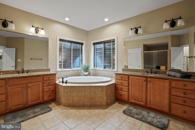 bathroom with tile patterned flooring, a shower stall, two vanities, a bath, and recessed lighting