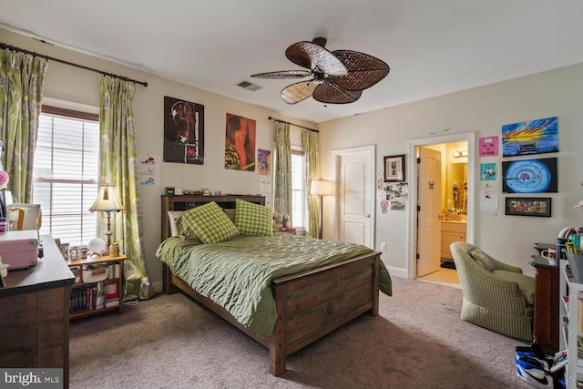 carpeted bedroom featuring ensuite bath, baseboards, and ceiling fan