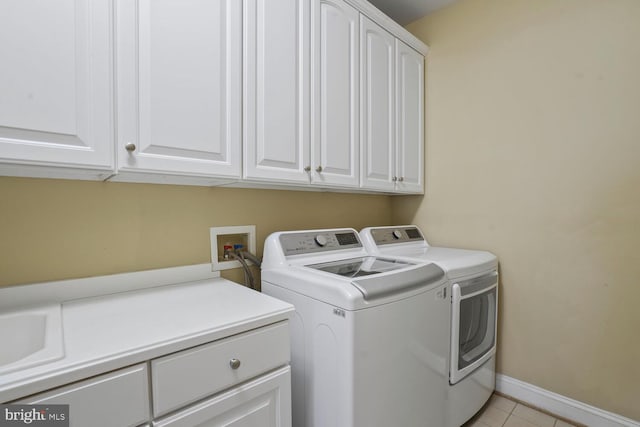 clothes washing area featuring cabinet space, washer and dryer, light tile patterned floors, and baseboards